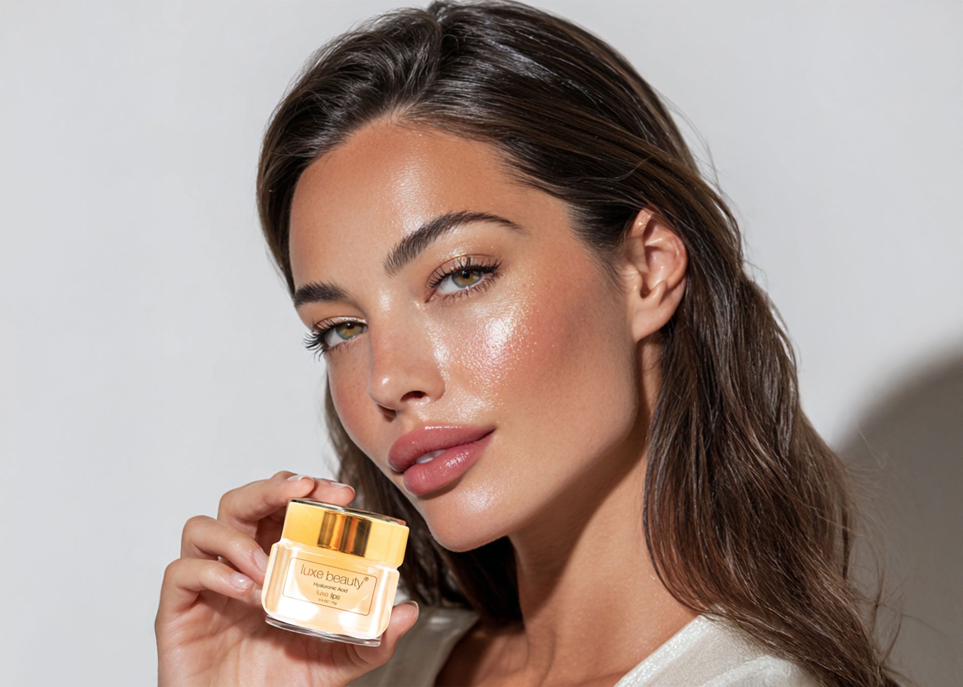 Woman holding a jar of Luxe Beauty Lip Plumper with a neutral background