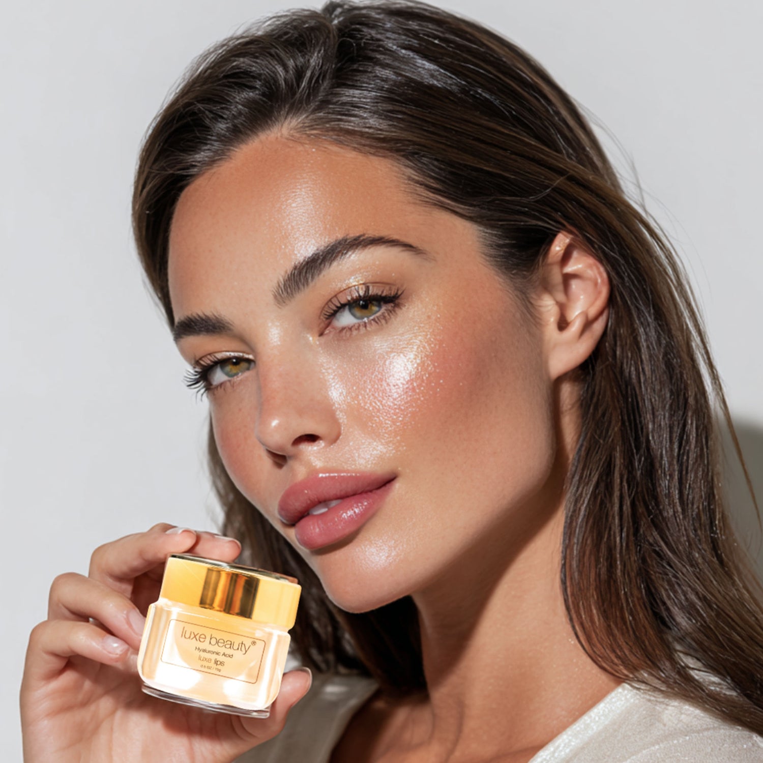 Woman holding a jar of Luxe Beauty Lip Plumper with a neutral background