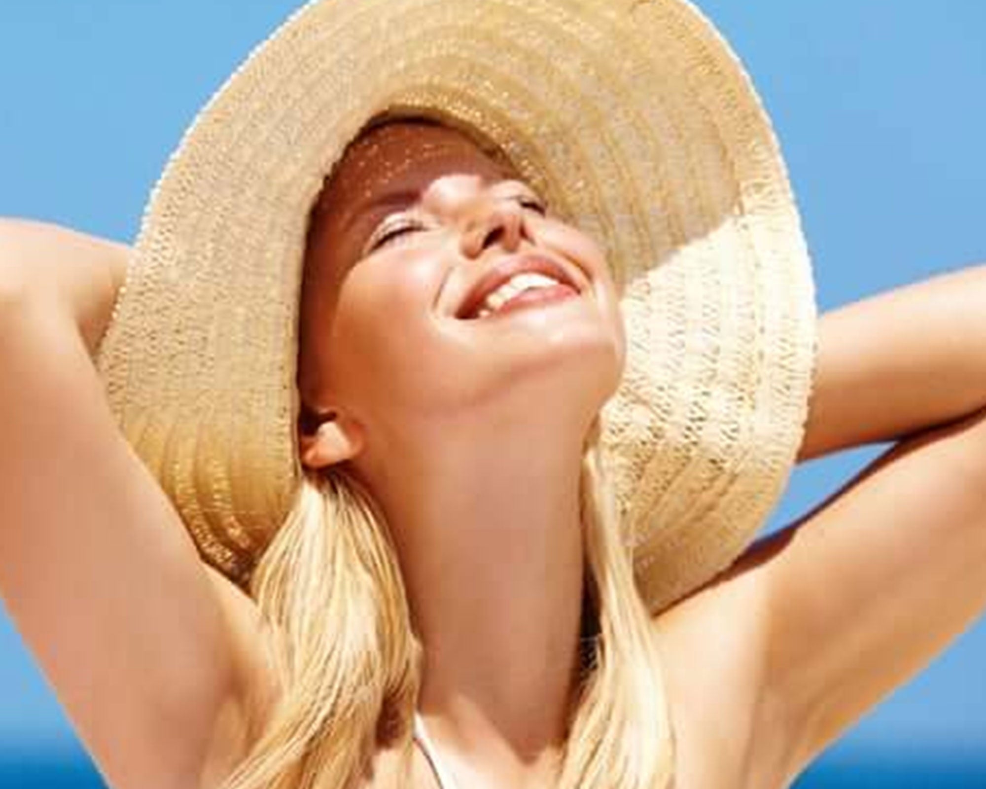 Woman wearing a straw hat against a clear blue sky