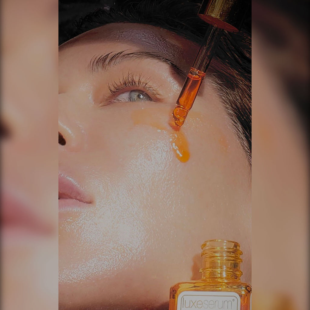 Close-up of a dropper with a serum being applied to a person's face, with Luxe Serum bottle in the foreground.