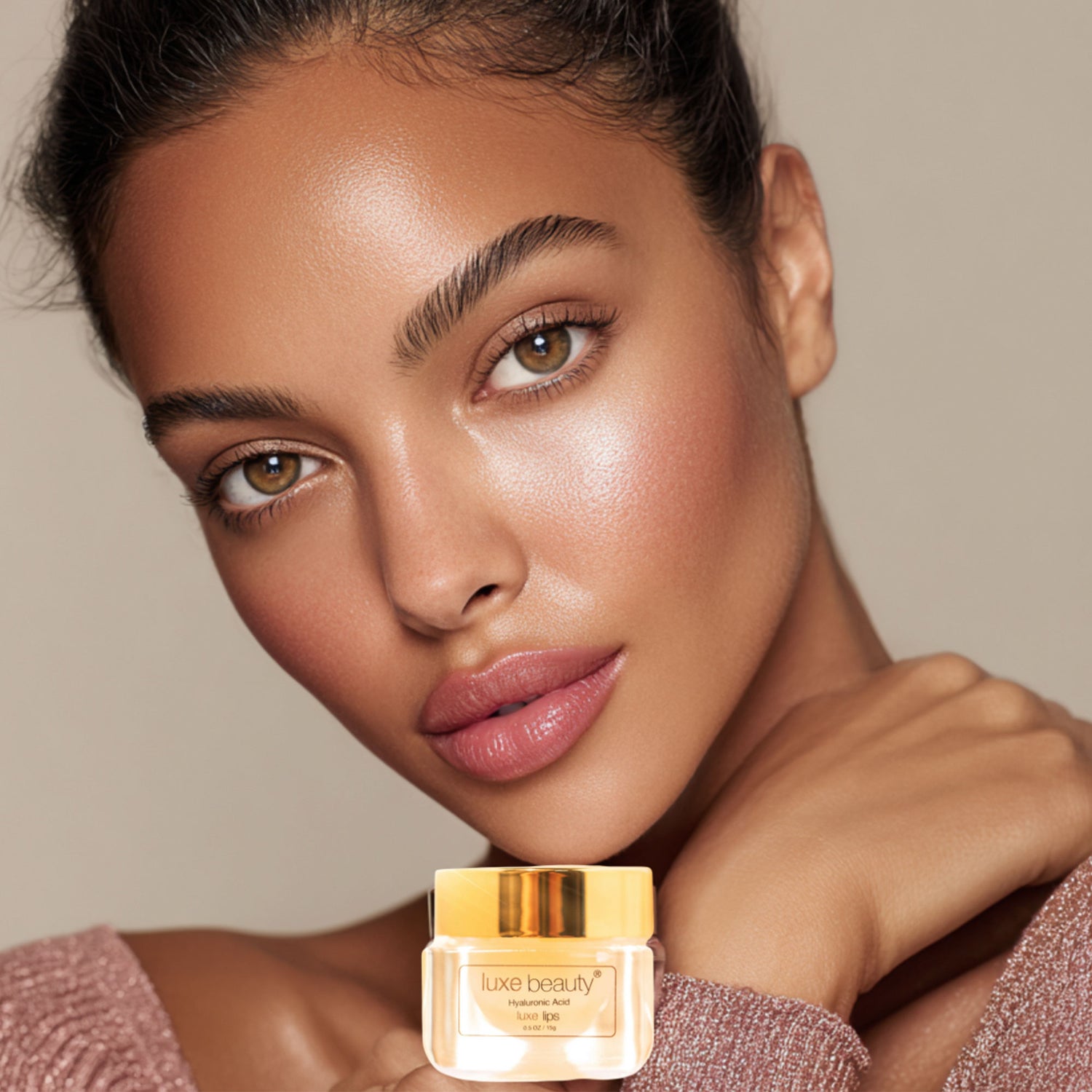Woman holding a jar of Luxe Beauty Luxe Lip Plumper against a neutral background