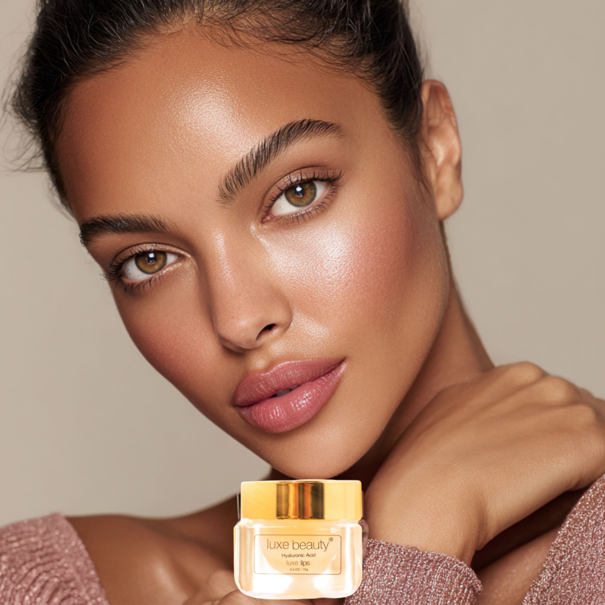 Woman holding a jar of Luxe Beauty Luxe Lip Plumper against a neutral background