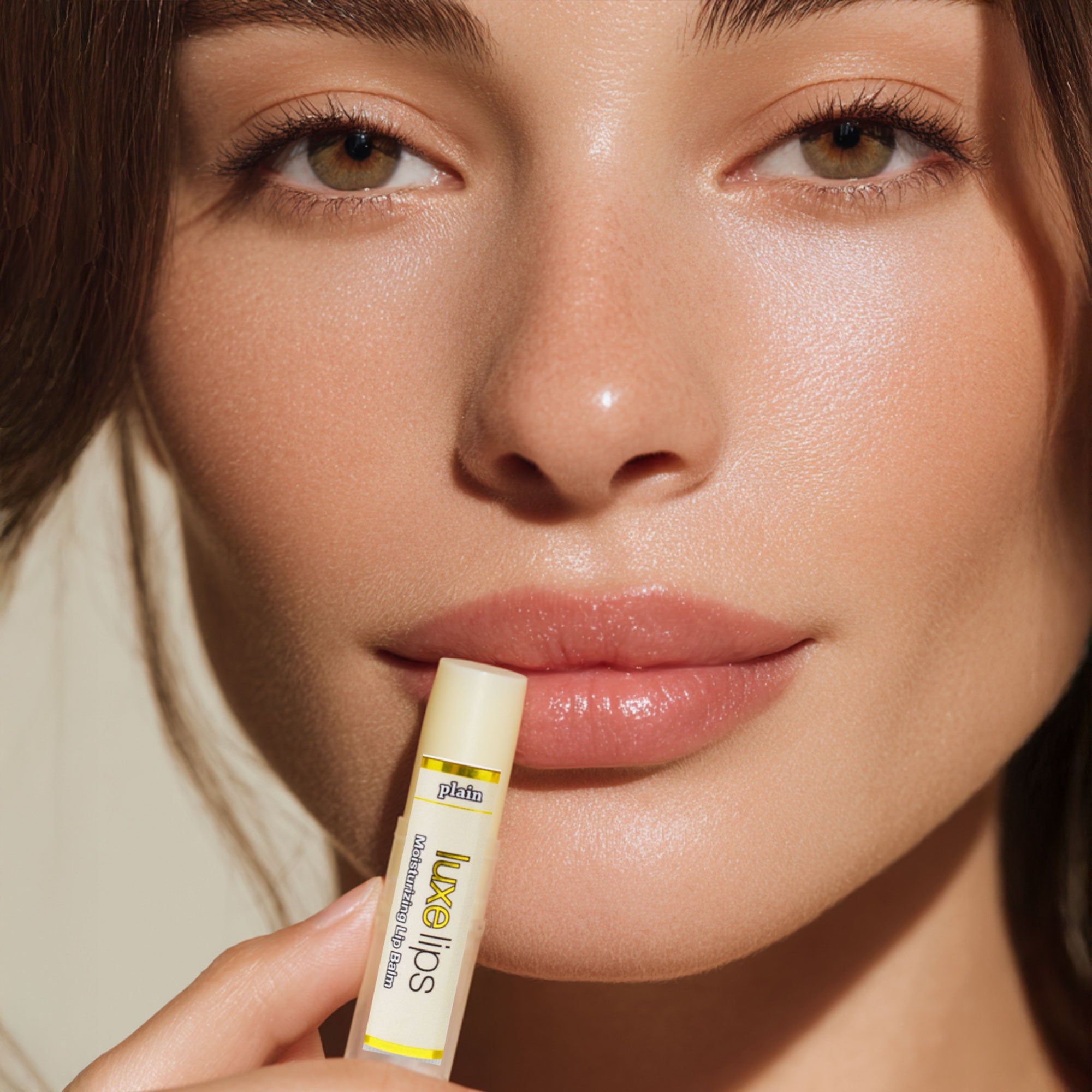 Close-up of a woman holding a Luxe Lips lip balm with a visible brand name.